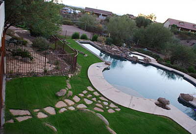 a backyard with a lush green sod lawn, stepping stones and a beautiful pool