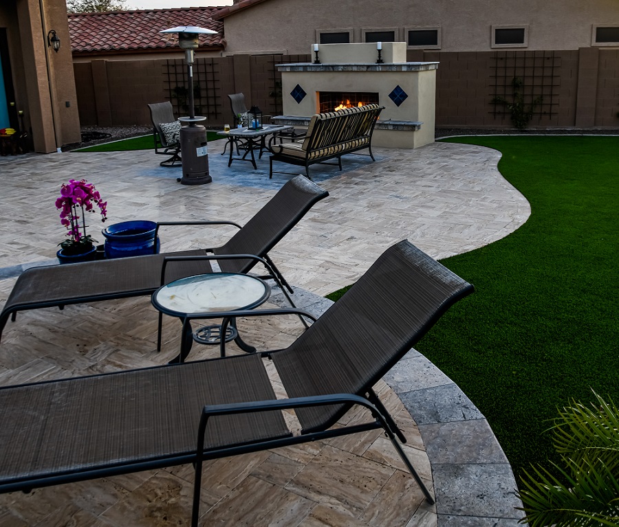 Photograph of a backyard in winter, featuring a lush green lawn and outdoor fireplace.
